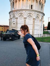 Side view of young woman standing against buildings in city