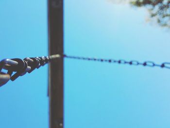 Low angle view of swing chain against blue sky