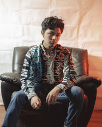 Portrait of man sitting on chair at home