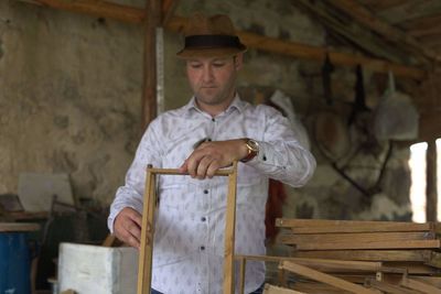 Man holding wood while standing in workshop