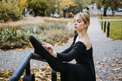 Ballerina dancing in autumn city street, modern ballet dancer in black dress, pointe shoes outdoors