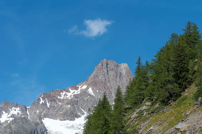 Low angle view of snowcapped mountains against blue sky