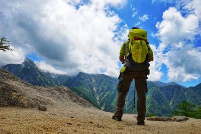 Rear view of man standing on mountain against sky