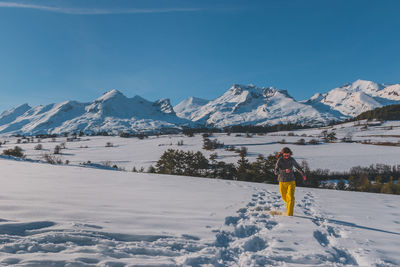 A full-body shot of a young caucasian woman running towards the camera in the french alps mountains