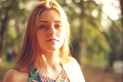 Close-up portrait of young woman against trees