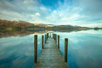 Wooden pier in lake against sky