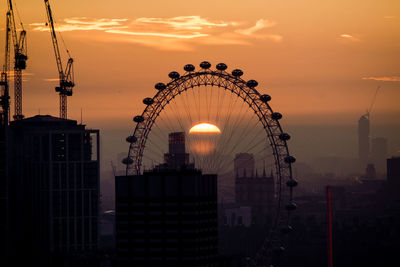 Silhouette ferris wheel against sky in city during sunset