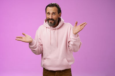 Midsection of man standing against pink background