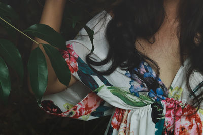 Close up of woman in floral dress against tropical leaves