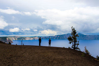 People standing on land against sky in crater lake