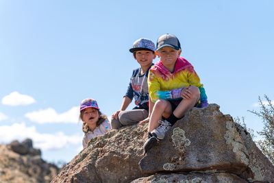 Children sitting on a rock looking at camera