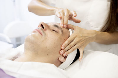 Close-up of a beautician's hands performing a facial massage on a man, skin care concept