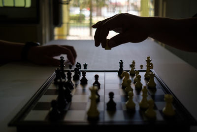 Cropped hands of people playing chess at home