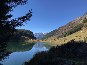 Scenic view of lake and mountains against clear blue sky