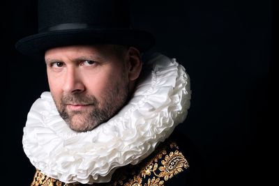 Close-up portrait of man wearing hat against black background