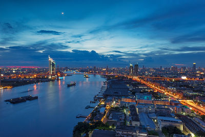 River amidst illuminated cityscape against sky at night