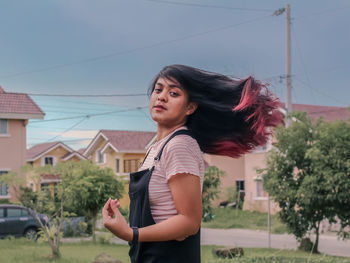 Portrait of young woman tossing hair while standing outdoors