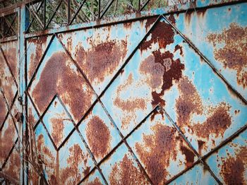 Full frame shot of rusty metal fence against wall