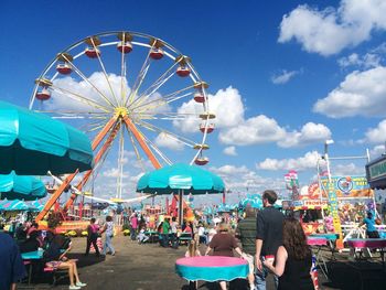 People in amusement park ride against sky