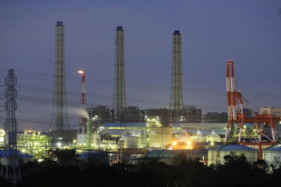 Illuminated factory against sky at night