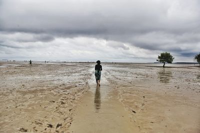 Rear view of man walking on beach