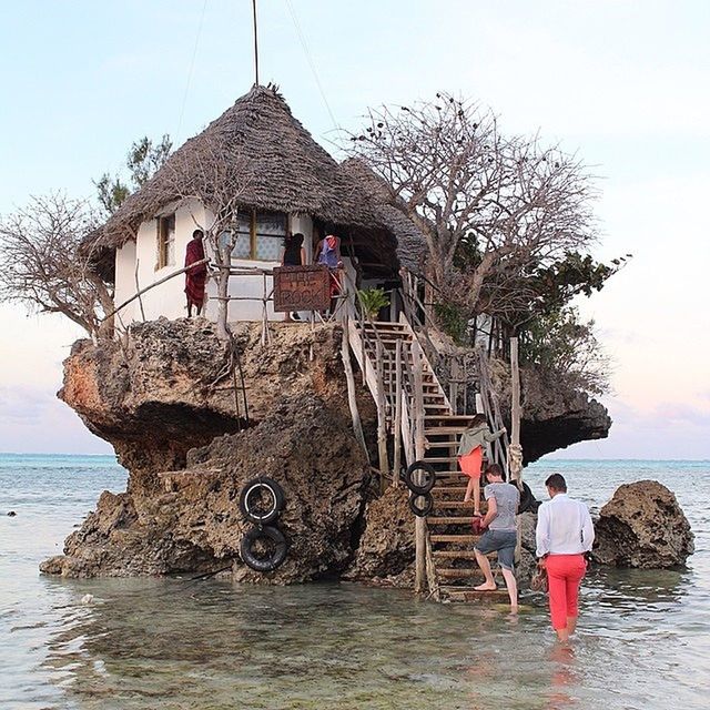 PEOPLE STANDING ON ROCK IN SEA