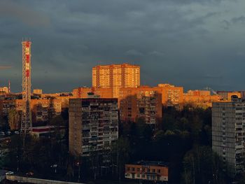 Buildings in city against storm clouds