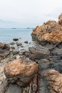 Rock formations on shore against sky