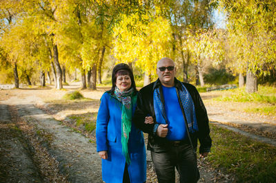 Portrait of mature couple walking in forest during autumn