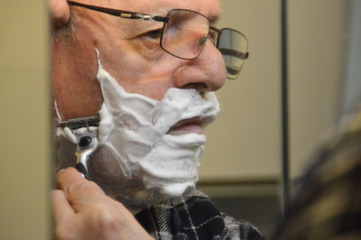 Senior man shaving his face in bathroom