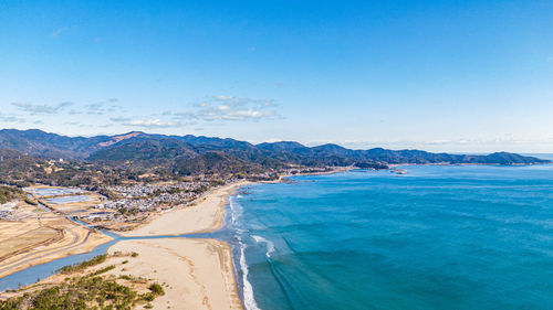 Scenic view of sea and mountains against blue sky