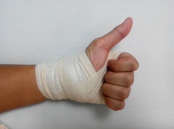 Cropped image of person hand covered with bandage showing thumbs up
