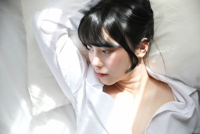 Portrait of young woman lying on bed