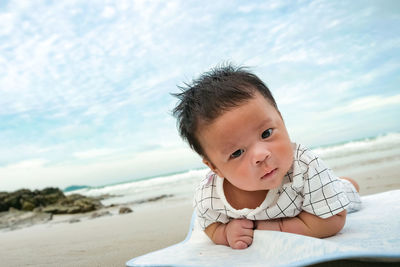 Portrait of cute boy at beach against sky