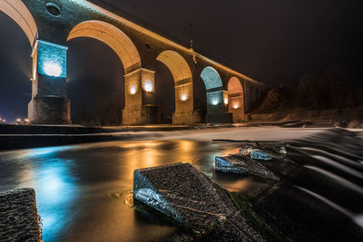 View of illuminated bridge over river at night