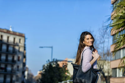 Portrait of smiling woman standing in city