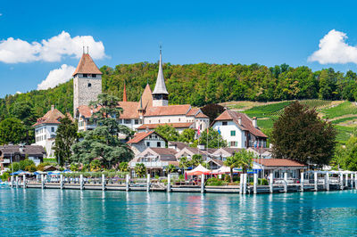 Buildings by river against sky