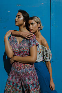 Young woman looking away against blue wall