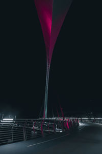 Illuminated bridge over river against sky at night