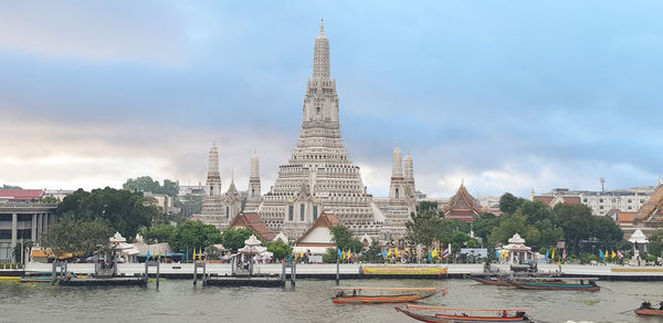 View of buildings by river against sky in city
