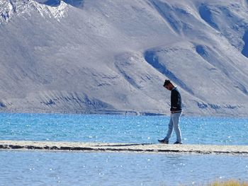 Full length of man standing on snowcapped mountain