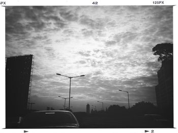 Cars on road against cloudy sky