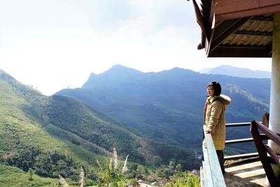 Woman standing in balcony against mountain 