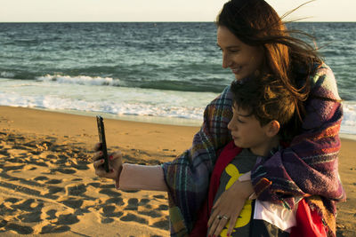 Mother and son taking a selfie on the beach in a cold day person