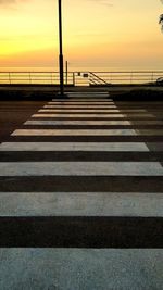 Scenic view of road by sea against sky during sunset