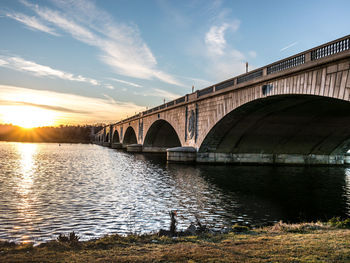 Bridge over river against sky during sunset
