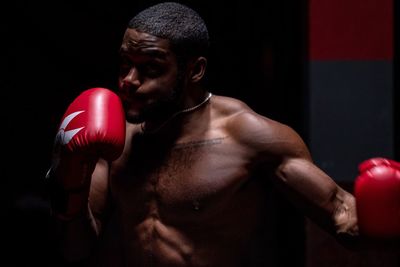 Full length of shirtless man standing against black background