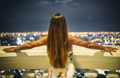 Rear view of woman standing by sea in city