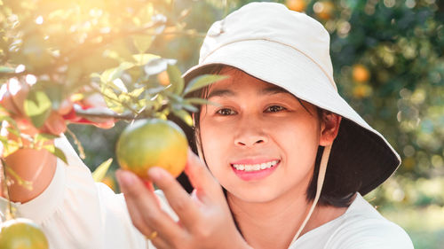 Close-up of smiling woman picking fruit from plants