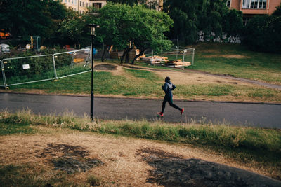 Full length of male athlete jogging on road in city